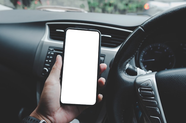 Driver holding a mobile phone in car with a white blank screen