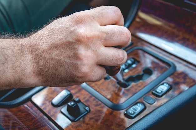 Driver man hand holding automatic transmission in car. Male hand changing levels of automatic gearbox in the car.