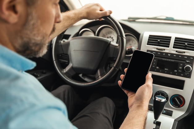 空の画面の運転車でスマートフォンを使用して運転手男