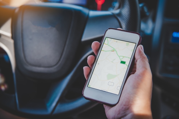 Driver sitting in the car and holding mobile smart phone with map gps navigation application