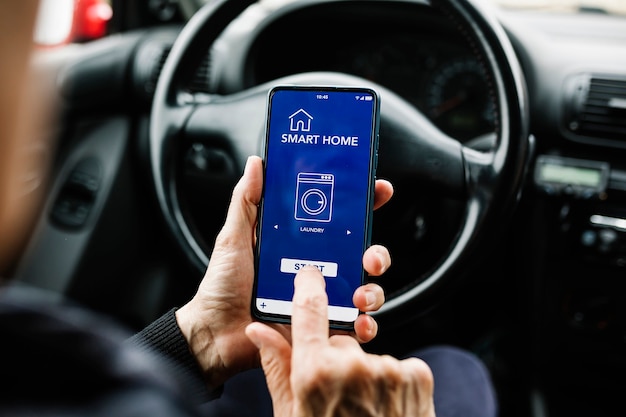 Driver using smart home app on smartphone in car  Internet of Things IOT concept