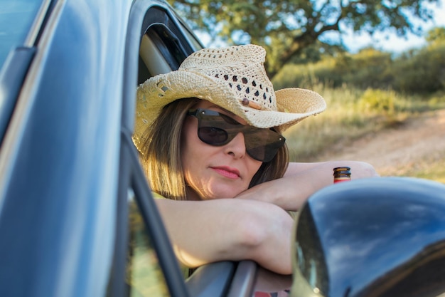 Driver Woman Resting In A Natural Park Inside The Car And Looking Out The Window.