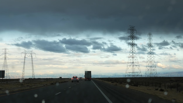 自動車の運転、米国カリフォルニア州のロードトリップ、車からの眺め。アメリカ合衆国を旅行するヒッチハイク。暴風雨の前の高速道路、山々、曇りの劇的な空。アメリカの風光明媚な小道。乗客のハメ撮り。