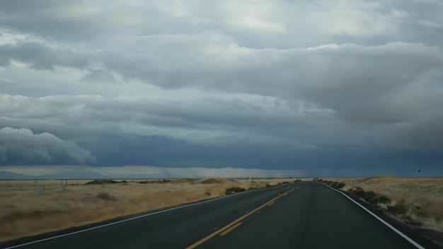 Driving car, road trip in California, USA. Highway, mountains, cloudy dramatic sky before rain storm