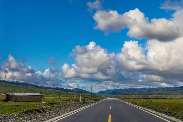 Driving down an empty road with a view of mountains in the distance and cloudy sky through a front