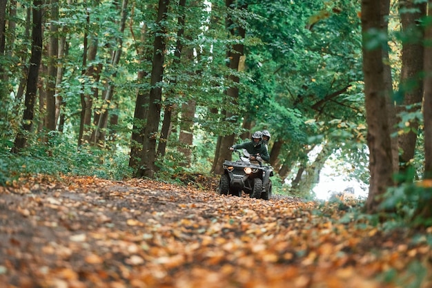 歩道を運転する若いカップルが森でクアッドバイクに乗っている