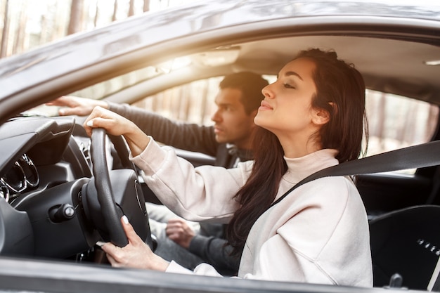 運転指導。若い女性が初めて車を運転することを学びます。彼女のインストラクターまたはボーイフレンドは彼女を助け、彼女に教えます