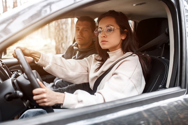 Driving instruction. A young woman learns to drive a car for the first time