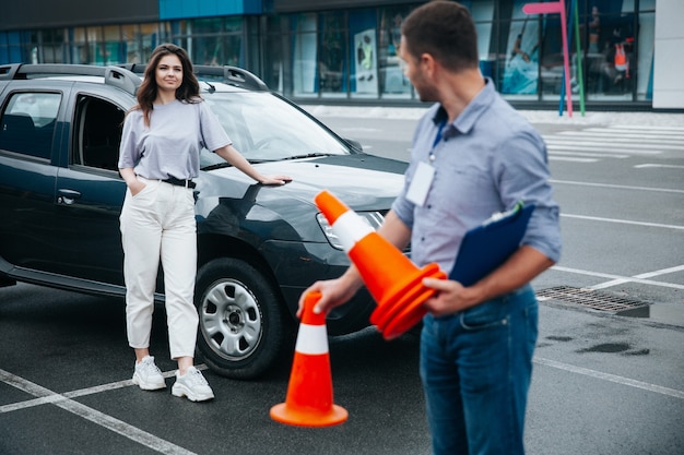 Istruttore di guida che raccoglie coni di plastica