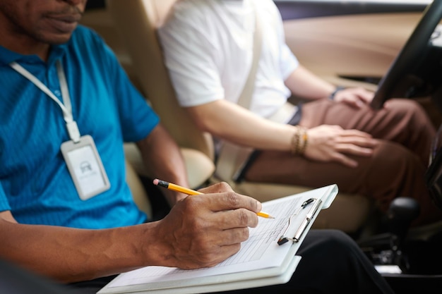 Photo driving instructor filling evaluation checklist