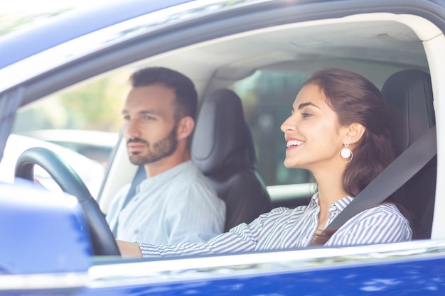 Guidare e parlare. bella moglie attraente che guida l'auto e parla con il suo bel marito handsome