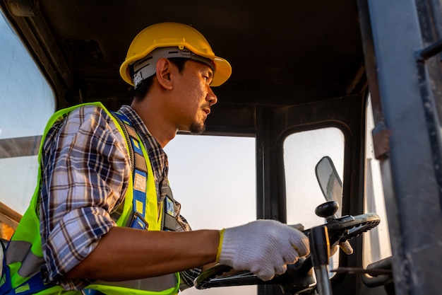 Driving worker heavy wheeled tractor, Wheel loader Excavator with backhoe unloading sand works in construction site.