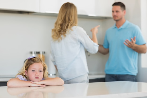 Droevig meisje die op lijst leunen terwijl ouders het debatteren