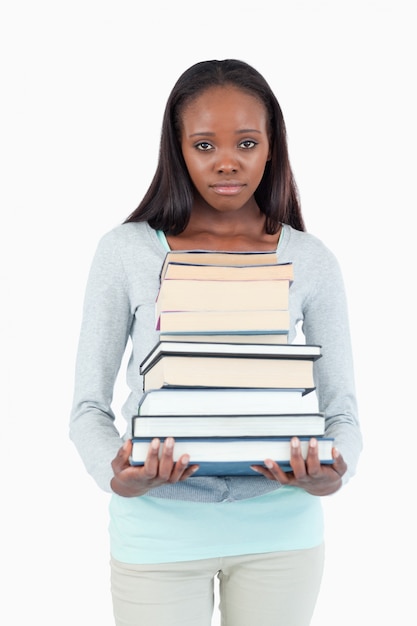 Droevig uitziende jonge vrouw met stapel boeken