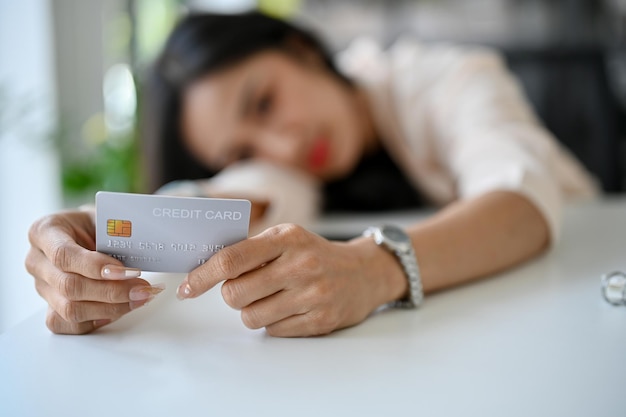 Droevige Aziatische vrouw ging op de tafel liggen met een creditcard die problemen had met haar creditcard