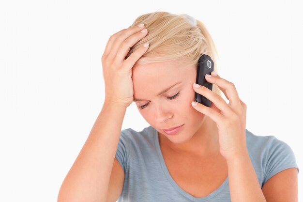 Droevige blonde vrouw op een telefoon