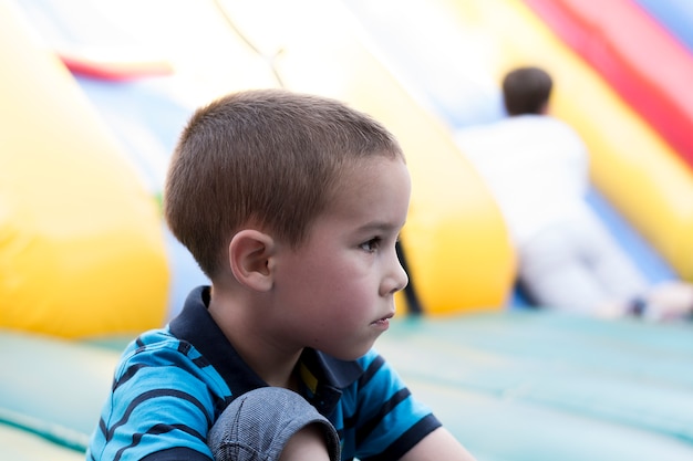 Foto droevige kleine jongen bij jonge geitjesspeelplaats