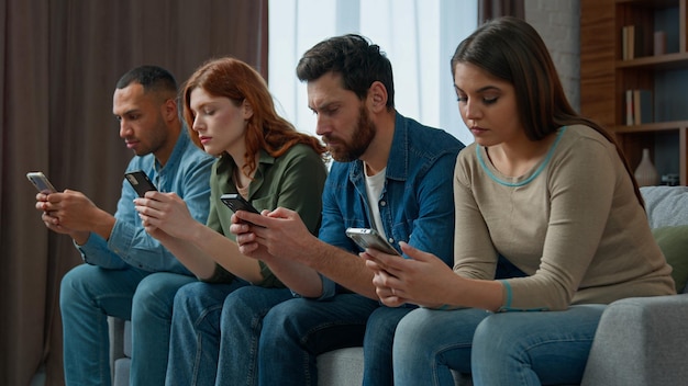 Droevige man kijk naar vrienden mobiele telefoon verslaafd multiraciale mensen verloren in gadgets overmatig gebruik van sociale