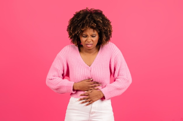 Droevige mooie jonge zwarte krullende vrouw die terloops lijdt aan maagpijn door menstruatiepijn