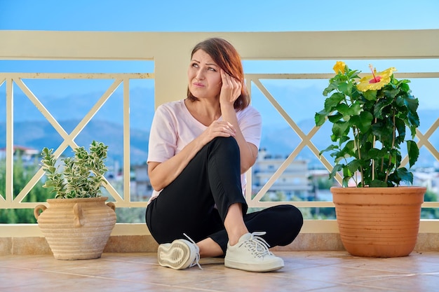 Droevige volwassen eenzame vrouw thuis op het terras