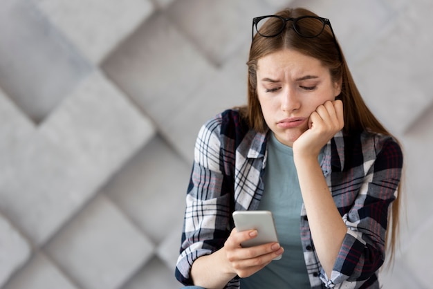 Droevige vrouw die haar telefoon controleert