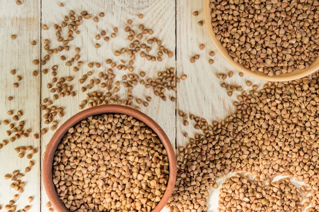 Droge boekweit in bruine kleikom op houten lijst. glutenvrij graan voor een gezond dieet