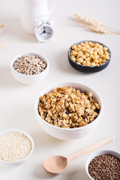Droge granola sesamzaad lijnzaad zonnebloempitten kikkererwten en quinoa in kommen Verticaal