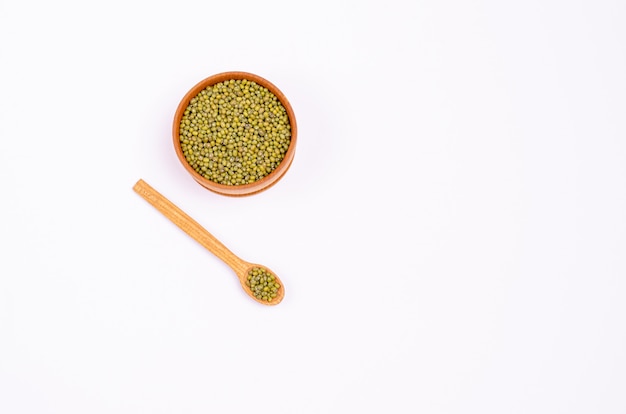 Droge groene linzen voor veganisten in een houten lepel en kom op een witte achtergrond, exemplaarruimte, plaats voor tekst.