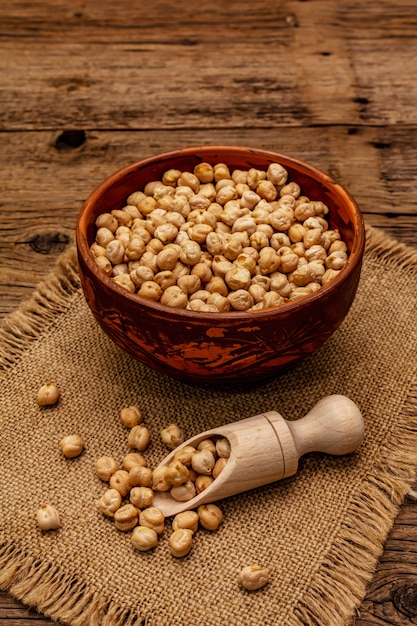 Droge kikkererwten in keramische kom op oude houten tafel. Traditioneel ingrediënt voor het koken van hummus