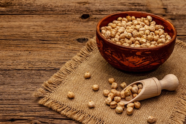 Droge kikkererwten in keramische kom op oude houten tafel. Traditioneel ingrediënt voor het koken van hummus