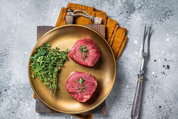 Foto droge leeftijd filet mignon biefstuk met kruiden rauw marmer vlees grijze achtergrond bovenaanzicht