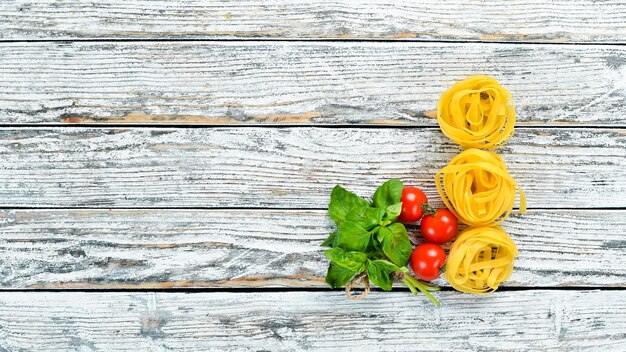 Droge pasta en ingrediënten op een witte houten achtergrond Bovenaanzicht Vrije ruimte voor uw tekst