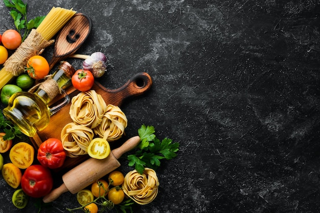 Droge pasta tomaten greens olie en ingrediënten Italiaanse traditionele keuken Verse groenten Bovenaanzicht Vrije ruimte voor uw tekst