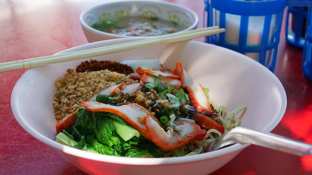 Droge rode varkensnoedels Gele noedels en gekookte groenten met geroosterd varkensvlees beroemd straatvoedsel in Thailand
