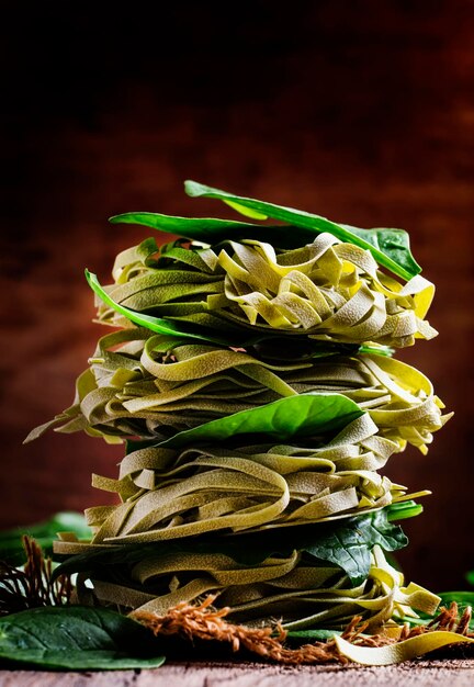 Droge spinazie pasta met groene bladeren gevouwen als een toren vintage houten achtergrond selectieve focus