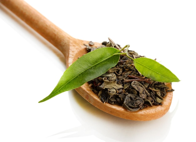 Droge thee met groene bladeren in houten lepel geïsoleerd op wit