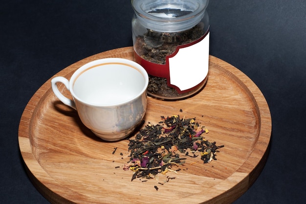 Droge thee met groene bladeren in houten lepels, op houten ondergrond.