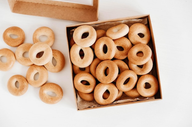 Drogen of ronde bagels in een papieren doos op een witte houten ondergrond