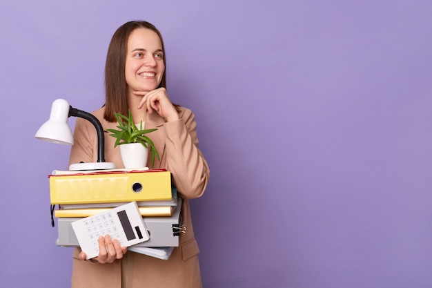 Dromende vrouw kantoormedewerker met kartonnen doos met haar spullen geïsoleerd op paarse achtergrond wegkijkend naar advertentieruimte kopie ruimte voor promotionele tekst