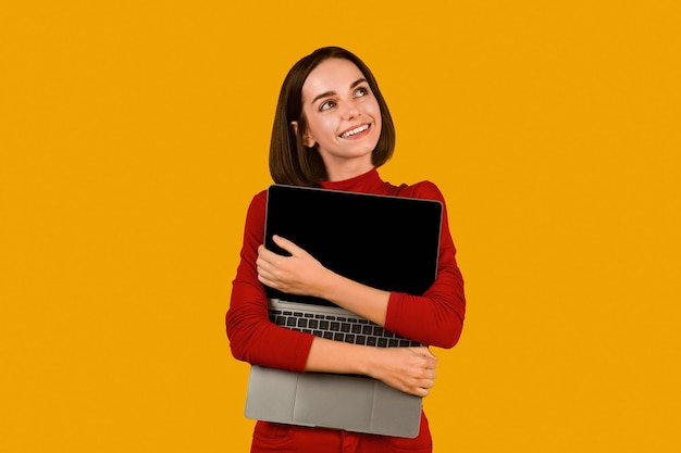 Dromerige jonge vrouw knuffelen laptop met leeg scherm