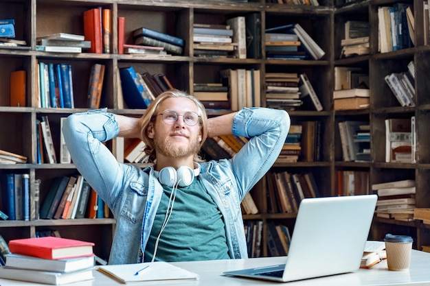 Dromerige ontspannen man student rusten klaar studiewerk zitten in de bibliotheek