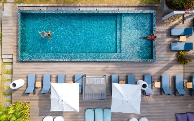 Drone aerial view from abotve at poolpraslin seychellescouple men and women in pool during vacation at a luxury resort at the beach of anse volbert tropical island with withe beaches and palm trees