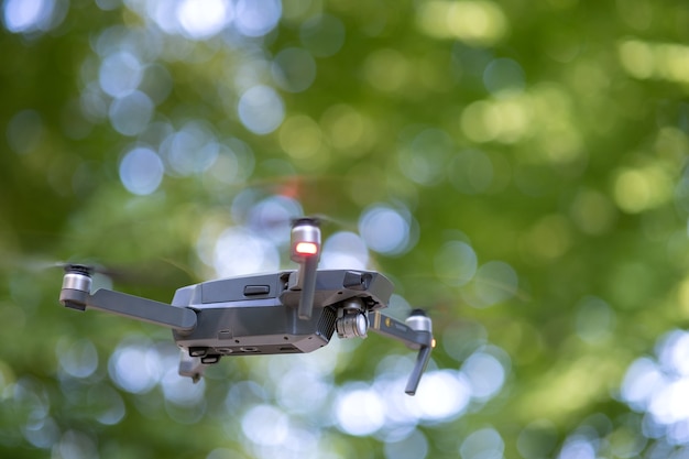 Drone copter with blurred propellers and video camera flying in air.