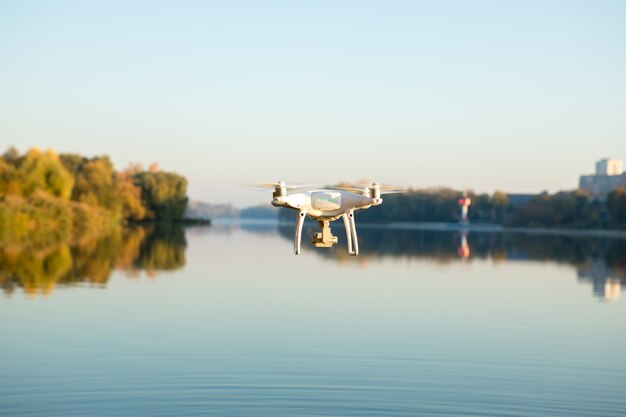 Photo drone copter with digital camera, blur river on background