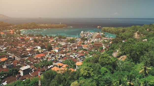 Drone flight over jungle village ocean bay houses harbor port pier in sunset light travel tourism