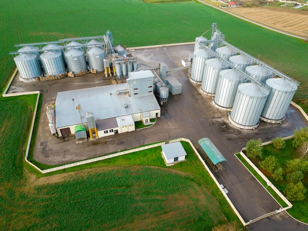 Drone flight over a large agroindustrial complex and barrels of grain silos at the agro manufacturing plant for processing drying cleaning and storage of agricultural products flour cereals