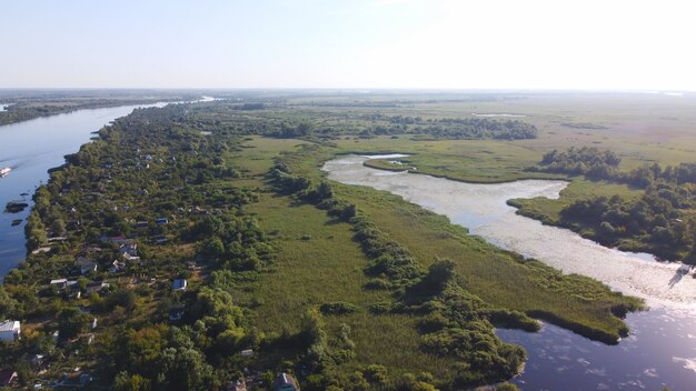 Drone fly over waving river of blue color surrounded by local village with various buildings