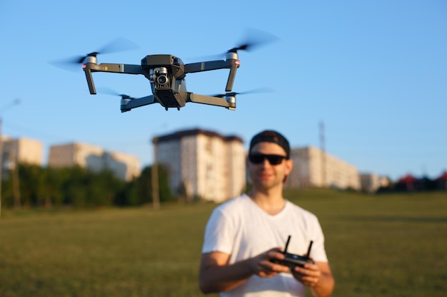 Drone hovers in front of man with remote controller in his hands quadcopter flies near pilot guy