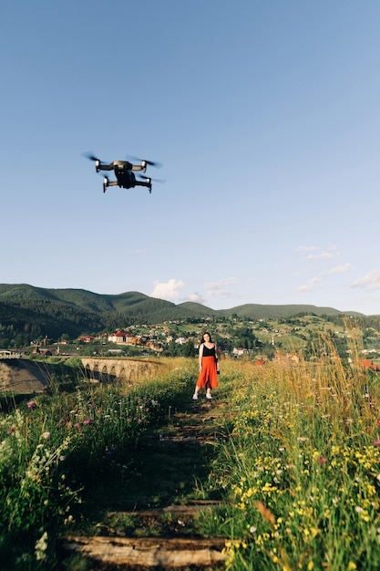 Drone in het veld op de achtergrond van een meisje in een rode jurk die op de brug loopt Drone en toerist op de oude spoorbrug