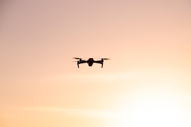 Дрон в полете на закате Видеосъемка сверху Статья о выборе квадрокоптера Плюсы и минусы дрона